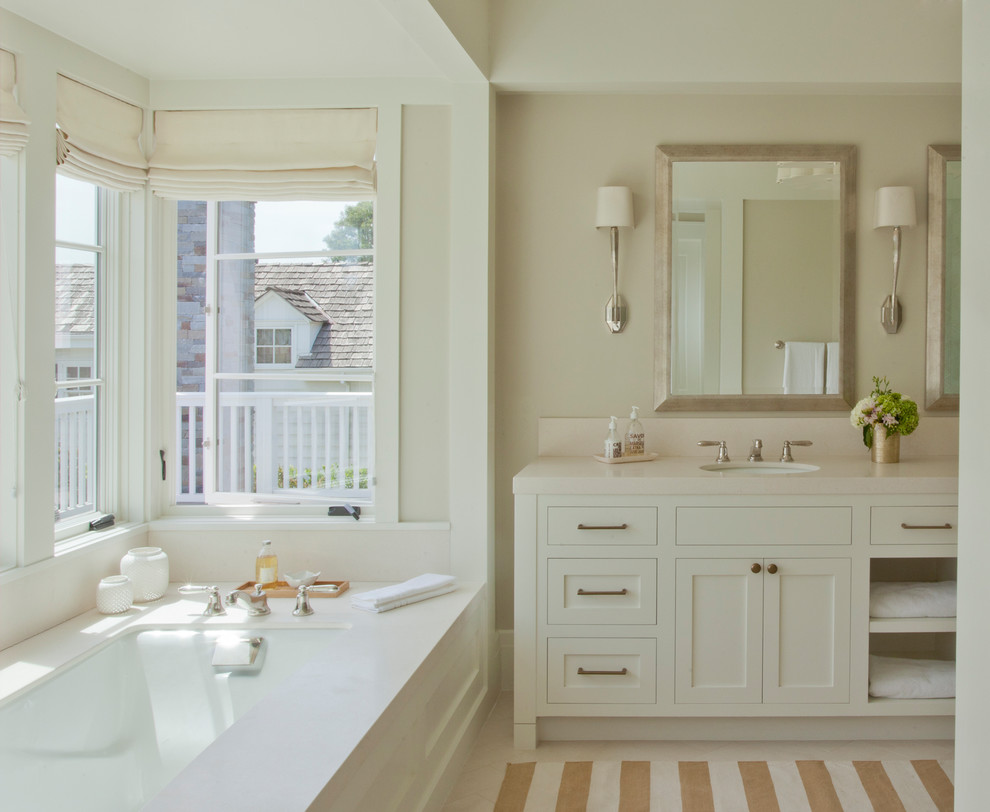 Идея дизайна: главная ванная комната среднего размера в классическом стиле с фасадами в стиле шейкер, белыми фасадами, полновстраиваемой ванной, бежевыми стенами, врезной раковиной, столешницей из искусственного кварца и бежевой столешницей