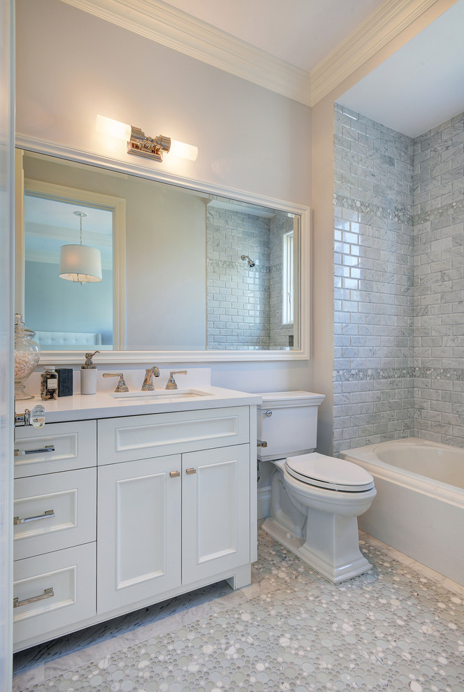 На фото: серо-белая ванная комната в классическом стиле с врезной раковиной, фасадами с утопленной филенкой, белыми фасадами, ванной в нише, душем над ванной, раздельным унитазом, белой плиткой, серыми стенами и полом из мозаичной плитки