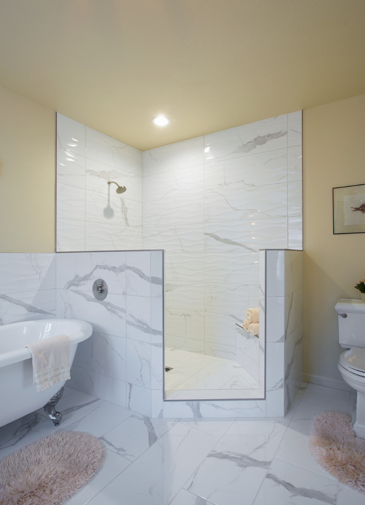 Cette image montre une salle de bain principale traditionnelle de taille moyenne avec un placard à porte shaker, des portes de placard beiges, une baignoire sur pieds, une douche d'angle, WC séparés, un carrelage gris, un carrelage blanc, un carrelage de pierre, un mur beige, un sol en marbre, un lavabo encastré, un plan de toilette en surface solide, un sol blanc et aucune cabine.