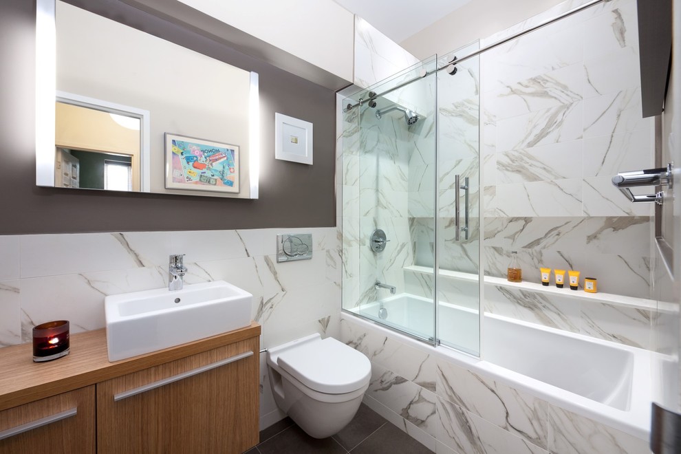 Bathroom - mid-sized modern white tile and stone tile porcelain tile bathroom idea in New York with flat-panel cabinets, light wood cabinets, a wall-mount toilet, brown walls, a vessel sink and wood countertops
