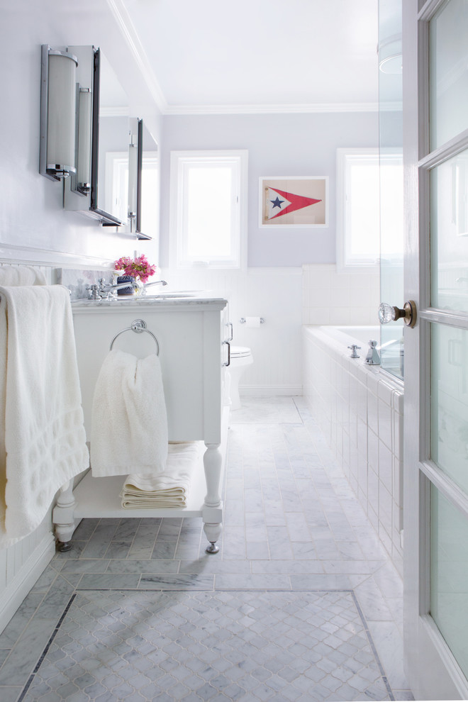 На фото: главная ванная комната среднего размера в классическом стиле с фасадами островного типа, белыми фасадами, угловой ванной, угловым душем, унитазом-моноблоком, белой плиткой, каменной плиткой, серыми стенами, мраморным полом, врезной раковиной, мраморной столешницей и серым полом