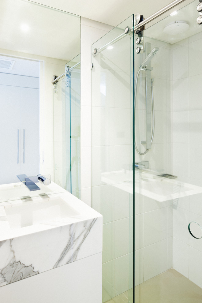 Modern inredning av ett litet badrum, med ett undermonterad handfat, vita skåp, marmorbänkskiva, en öppen dusch, vit kakel, porslinskakel, vita väggar, klinkergolv i porslin och dusch med skjutdörr