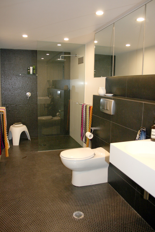 Cette photo montre une grande salle de bain principale moderne avec un lavabo suspendu, un placard à porte vitrée, une douche ouverte, WC suspendus, un carrelage noir, mosaïque, un mur blanc et un sol en carrelage de terre cuite.