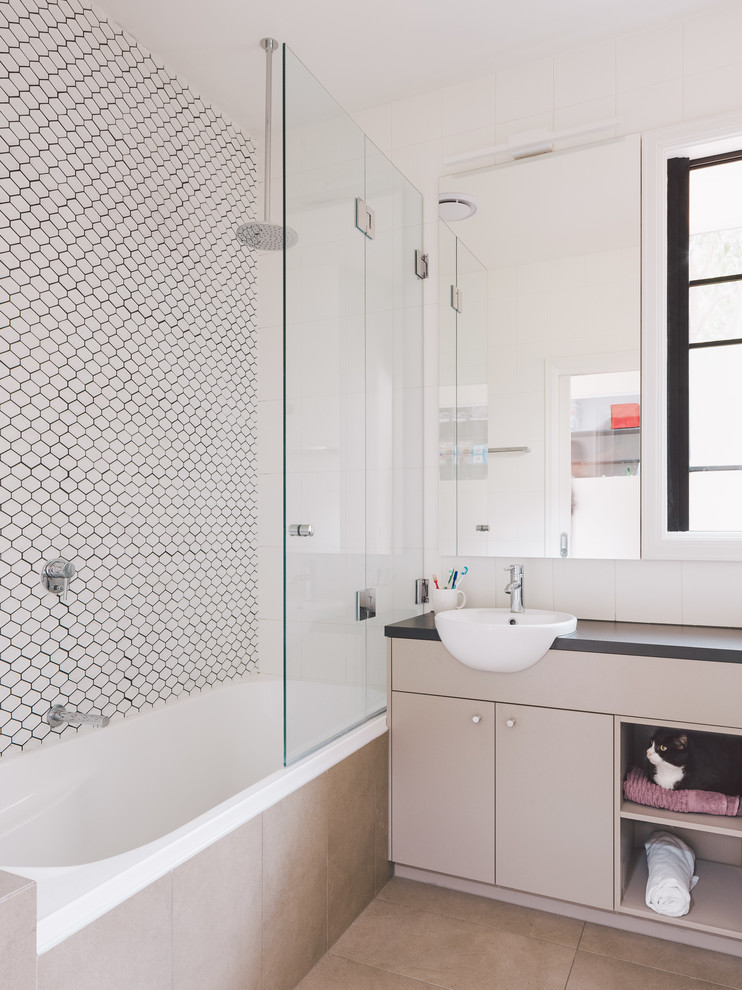 Bild på ett mellanstort funkis en-suite badrum, med luckor med profilerade fronter, grå skåp, ett hörnbadkar, en dusch/badkar-kombination, vit kakel, keramikplattor, vita väggar, klinkergolv i keramik, ett integrerad handfat och bänkskiva i terrazo