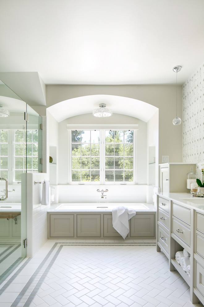 Foto på ett vintage vit badrum, med luckor med profilerade fronter, grå skåp, ett undermonterat badkar, beige väggar, ett undermonterad handfat och vitt golv
