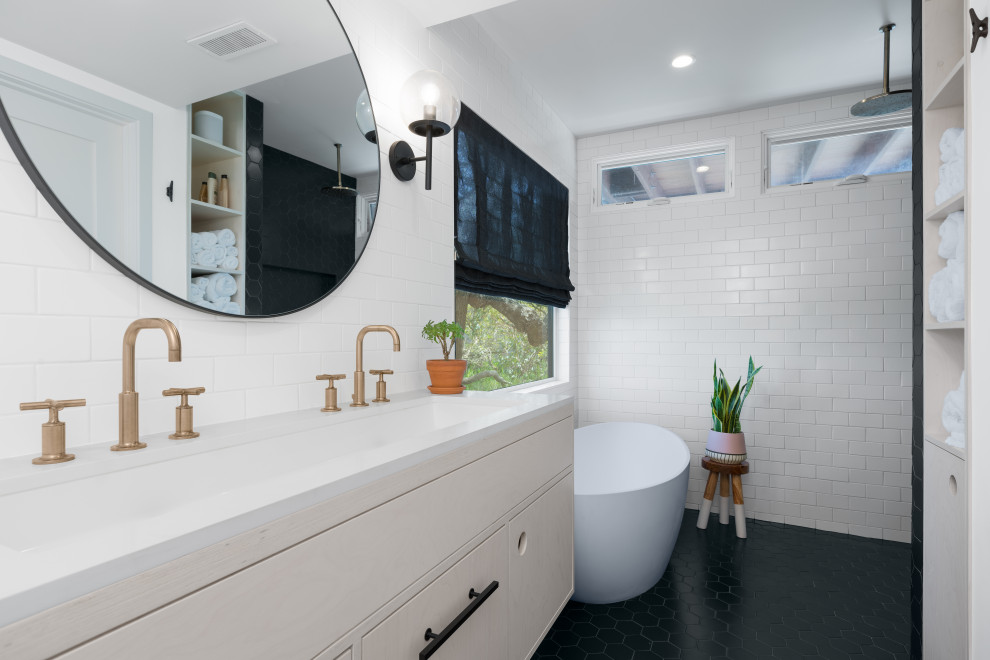 This is an example of a small coastal ensuite bathroom in Other with flat-panel cabinets, light wood cabinets, a freestanding bath, a walk-in shower, a two-piece toilet, black and white tiles, ceramic tiles, white walls, porcelain flooring, a submerged sink, engineered stone worktops, black floors, a hinged door, white worktops, a wall niche, double sinks and a floating vanity unit.