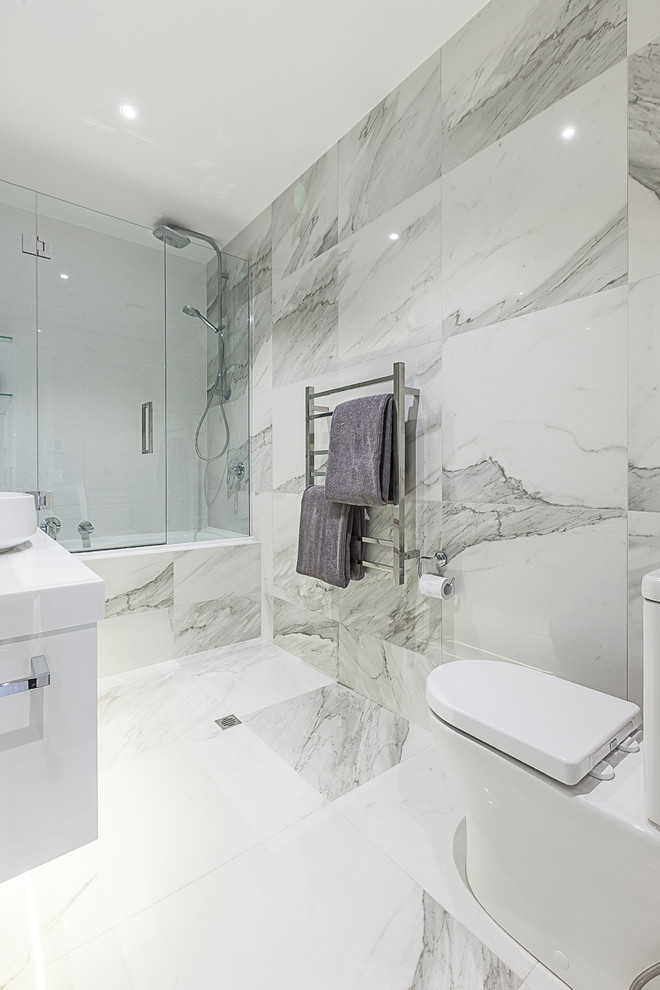 Пример оригинального дизайна: главная ванная комната среднего размера в современном стиле с ванной в нише, душем над ванной, унитазом-моноблоком, настольной раковиной, душем с распашными дверями, белыми фасадами, мраморной плиткой, мраморным полом и столешницей из искусственного камня