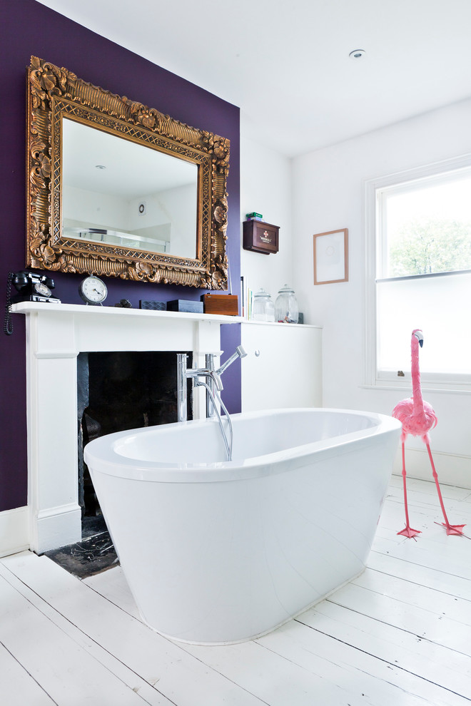 Modelo de cuarto de baño ecléctico con bañera exenta, paredes púrpuras y suelo de madera pintada