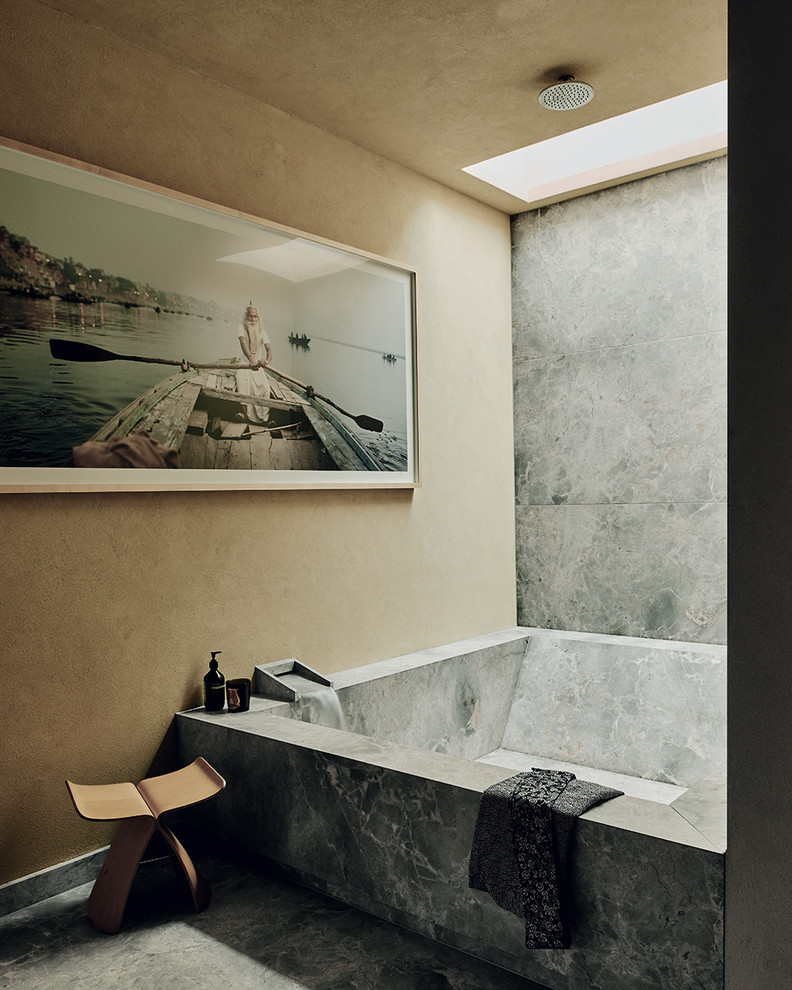 На фото: ванная комната в восточном стиле с ванной в нише, душем над ванной, серой плиткой, бежевыми стенами, серым полом и открытым душем