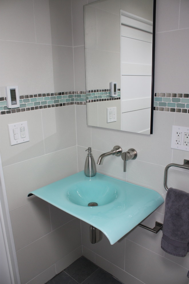Inspiration pour une salle de bain design avec un carrelage blanc, des carreaux de porcelaine, un mur blanc, un lavabo intégré et un plan de toilette en verre.