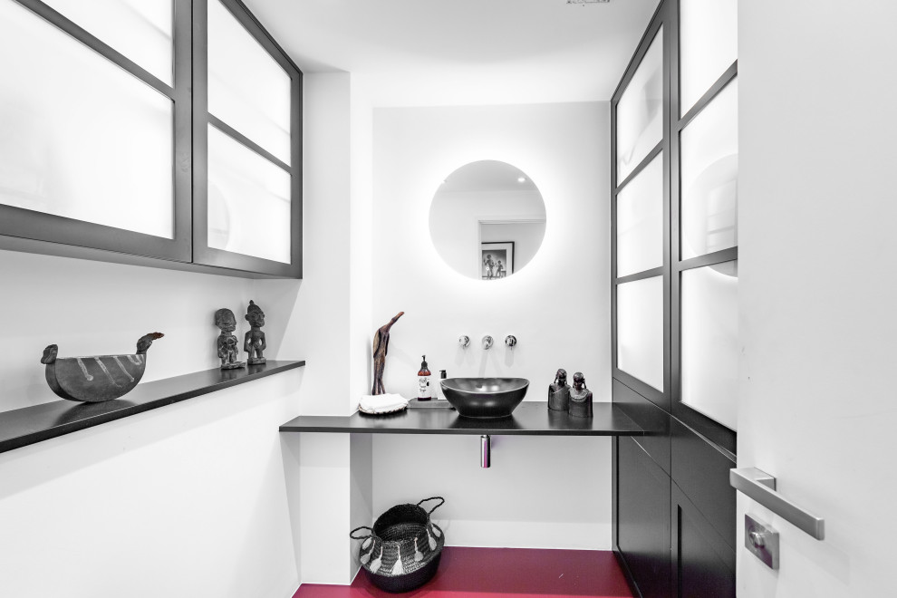 Ejemplo de cuarto de baño único y flotante contemporáneo pequeño con puertas de armario negras, sanitario de una pieza, encimera de madera, suelo rojo y encimeras negras