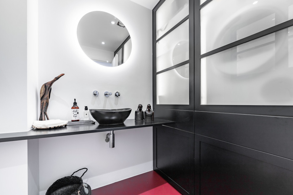 Immagine di una piccola stanza da bagno design con ante nere, WC monopezzo, top in legno, pavimento rosso, top nero, un lavabo e mobile bagno sospeso