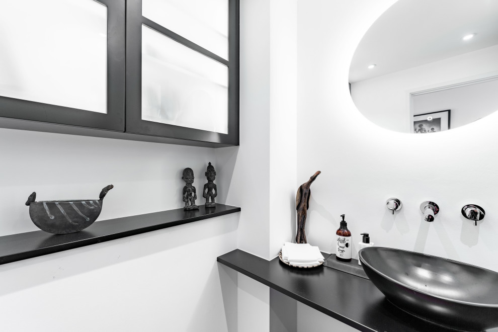 Foto di una piccola stanza da bagno minimal con ante nere, WC monopezzo, top in legno, pavimento rosso, top nero, un lavabo e mobile bagno sospeso