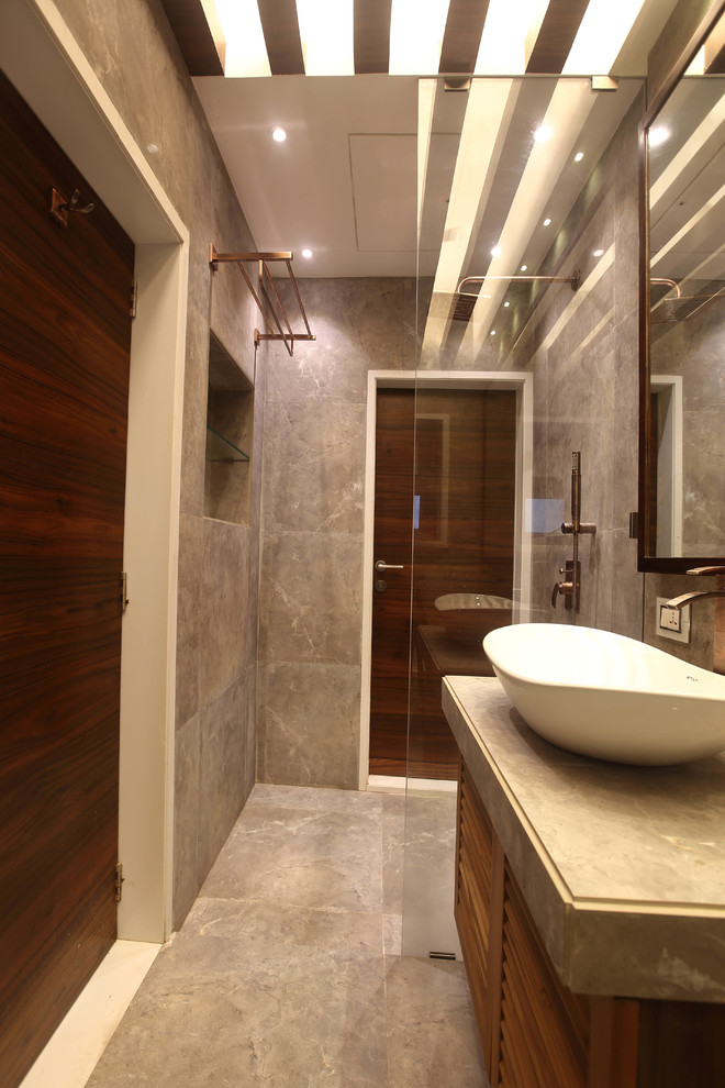 Bild på ett mellanstort funkis badrum med dusch, med luckor med lamellpanel, skåp i mellenmörkt trä, en toalettstol med separat cisternkåpa, grå kakel, stenkakel, grå väggar, klinkergolv i keramik och kaklad bänkskiva
