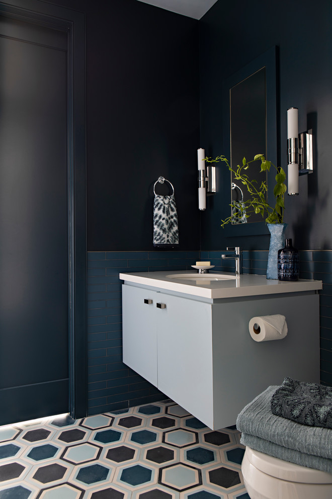 Bild på ett litet funkis vit vitt badrum med dusch, med släta luckor, blå skåp, blå kakel, glaskakel, cementgolv, ett undermonterad handfat, bänkskiva i kvarts, svarta väggar och flerfärgat golv
