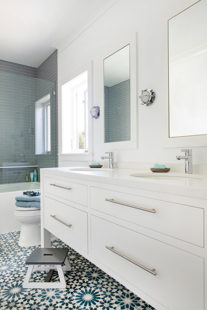 Пример оригинального дизайна: маленькая детская ванная комната в современном стиле с плоскими фасадами, белыми фасадами, ванной в нише, белой плиткой, стеклянной плиткой, белыми стенами, полом из цементной плитки, врезной раковиной, столешницей из искусственного кварца, синим полом, белой столешницей и душем над ванной для на участке и в саду