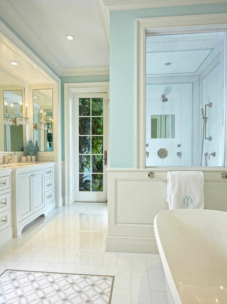 Cette photo montre une salle de bain principale chic avec un placard avec porte à panneau encastré, des portes de placard blanches, une baignoire indépendante, un mur bleu, un sol en carrelage de porcelaine, un lavabo encastré et un sol blanc.