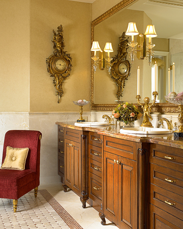 Imagen de cuarto de baño principal tradicional grande con lavabo encastrado, armarios con paneles con relieve, puertas de armario de madera en tonos medios, encimera de mármol, bañera exenta, ducha empotrada, bidé, baldosas y/o azulejos beige, baldosas y/o azulejos de piedra, paredes amarillas, suelo de mármol y suelo rojo