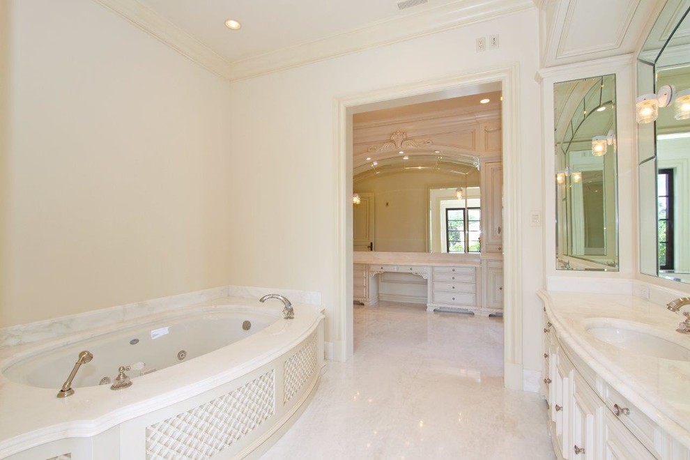 Foto di una grande stanza da bagno padronale tradizionale con consolle stile comò, ante bianche, vasca sottopiano, pareti beige, pavimento in marmo, lavabo sottopiano, top in marmo e pavimento bianco