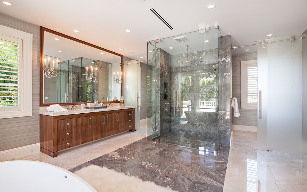Cette photo montre une très grande salle de bain principale chic en bois brun avec un placard à porte plane, une baignoire indépendante, une douche à l'italienne, un carrelage gris, des dalles de pierre, un mur gris, un sol en marbre et un plan de toilette en marbre.