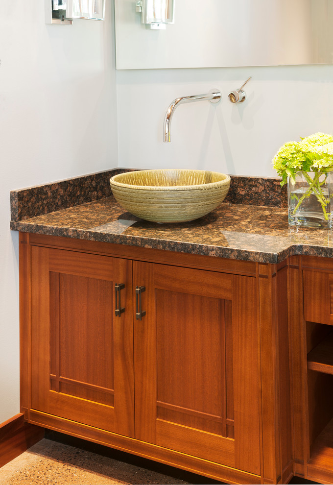 Cette image montre une grande salle de bain craftsman en bois brun avec un plan de toilette en granite, un placard avec porte à panneau encastré, un mur gris, sol en béton ciré, une vasque, un sol marron et un plan de toilette multicolore.
