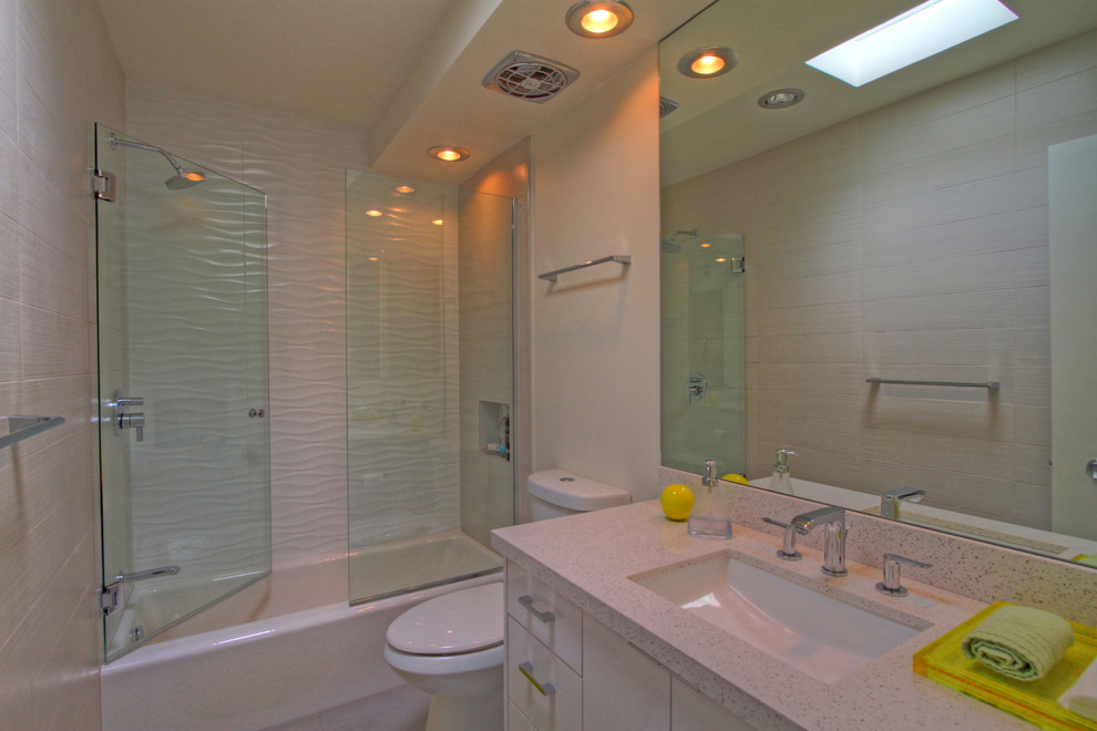 他の地域にあるお手頃価格の中くらいなモダンスタイルのおしゃれなバスルーム (浴槽なし) (フラットパネル扉のキャビネット、白いキャビネット、珪岩の洗面台、白いタイル、磁器タイル、ドロップイン型浴槽、シャワー付き浴槽	、アンダーカウンター洗面器、白い壁、磁器タイルの床、分離型トイレ、開き戸のシャワー) の写真