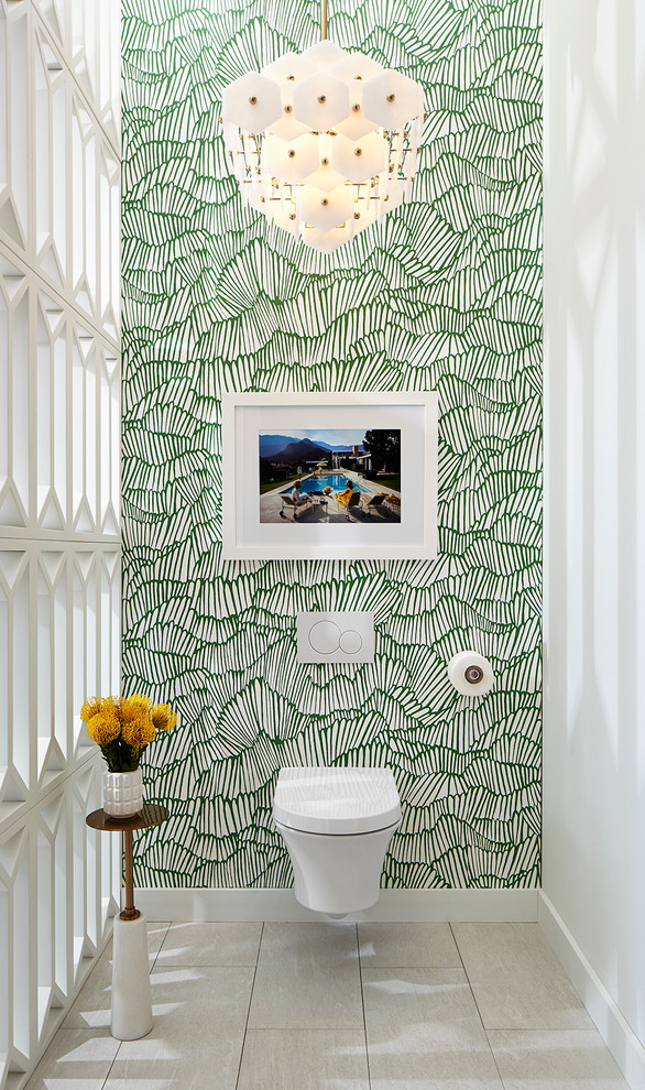 Cette image montre un grand WC suspendu minimaliste avec un placard à porte plane, des portes de placard blanches, un carrelage blanc, des carreaux de porcelaine, un mur vert, un sol en carrelage de porcelaine et un plan de toilette en marbre.