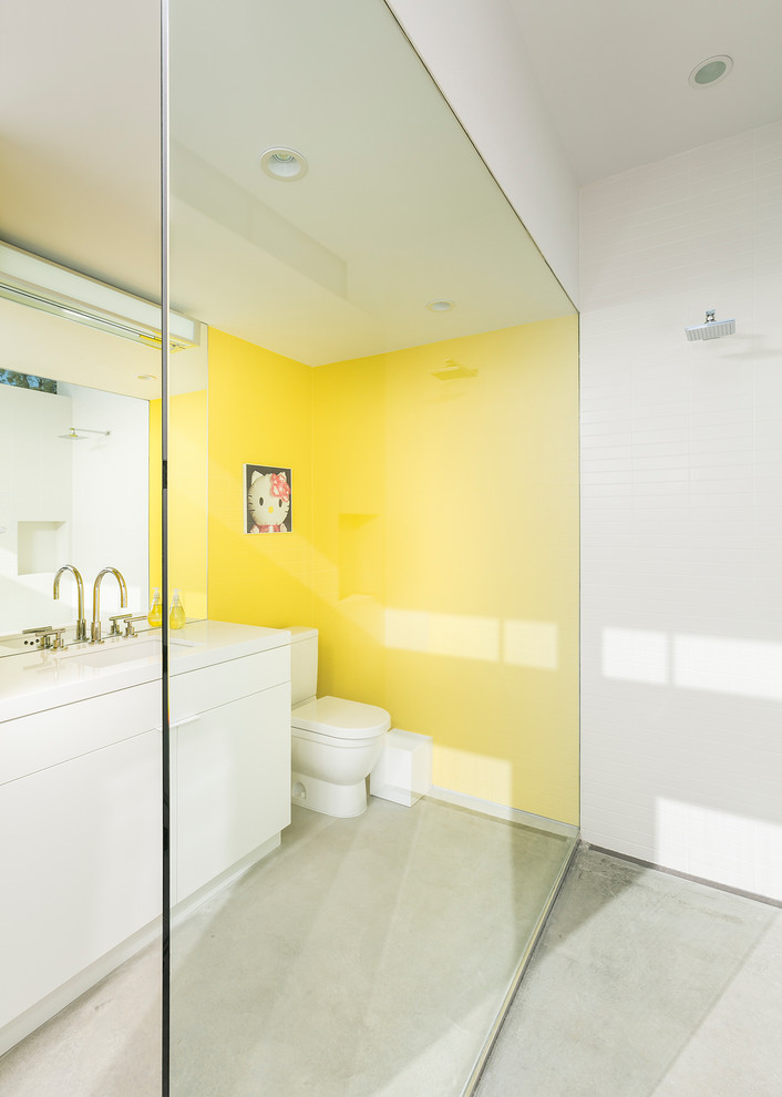 Inspiration för 60 tals badrum med dusch, med släta luckor, vita skåp, en kantlös dusch, en toalettstol med separat cisternkåpa, vit kakel, stickkakel, gula väggar, cementgolv, ett undermonterad handfat, grått golv och med dusch som är öppen