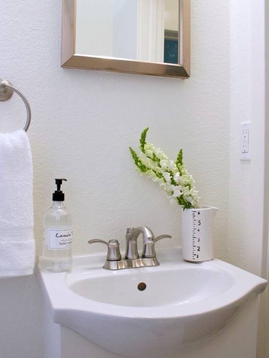 Example of a small minimalist bathroom design in Tampa with a pedestal sink, glass-front cabinets and white walls