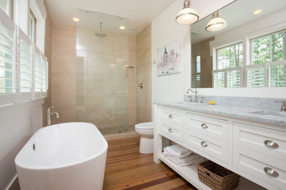 Bild på ett mellanstort vintage badrum, med luckor med infälld panel, vita skåp, ett fristående badkar, en öppen dusch, en toalettstol med hel cisternkåpa, brun kakel, vita väggar, mellanmörkt trägolv, ett undermonterad handfat och marmorbänkskiva