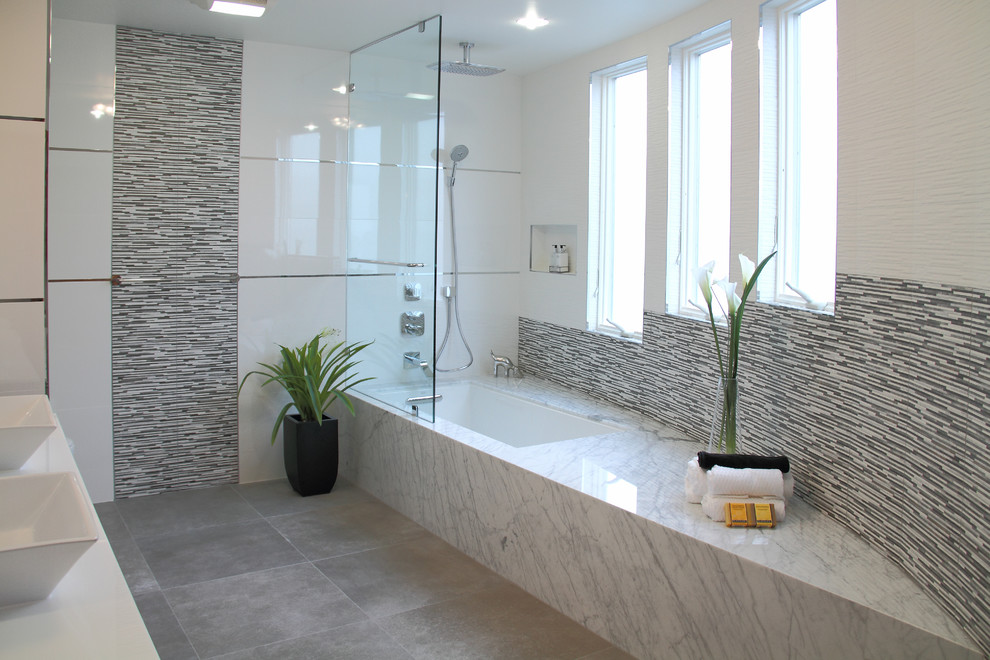 Cette image montre une salle de bain design avec un combiné douche/baignoire, un carrelage gris, des carreaux en allumettes et une baignoire encastrée.