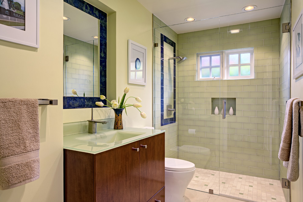 Пример оригинального дизайна: маленькая ванная комната в современном стиле с монолитной раковиной, плоскими фасадами, темными деревянными фасадами, стеклянной столешницей, унитазом-моноблоком, зеленой плиткой, стеклянной плиткой, зелеными стенами, полом из известняка, душевой кабиной и душем с распашными дверями для на участке и в саду