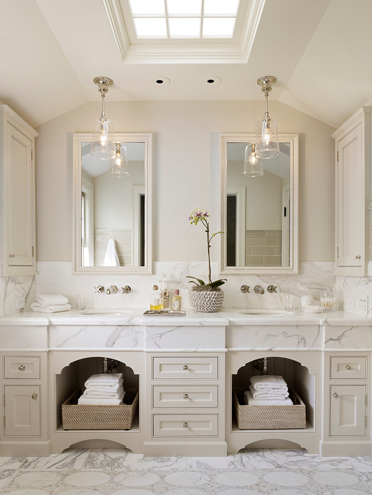 Modelo de cuarto de baño principal clásico con lavabo bajoencimera, puertas de armario beige, baldosas y/o azulejos blancos, paredes beige, armarios con paneles empotrados y espejo con luz