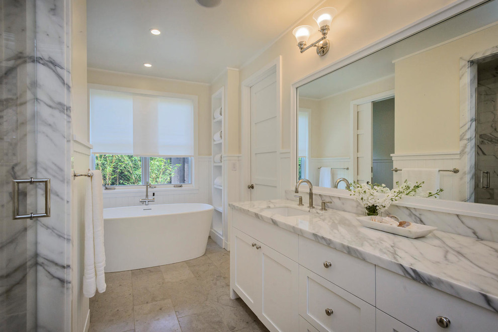 Bathroom - mid-sized cottage master beige tile and stone tile limestone floor bathroom idea in San Francisco with an undermount sink, shaker cabinets, white cabinets, marble countertops, a one-piece toilet and beige walls