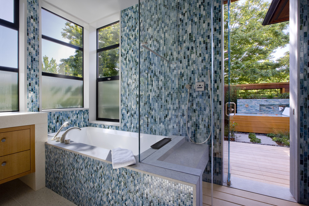 Пример оригинального дизайна: ванная комната в современном стиле с ванной в нише, синей плиткой и стеклянной плиткой