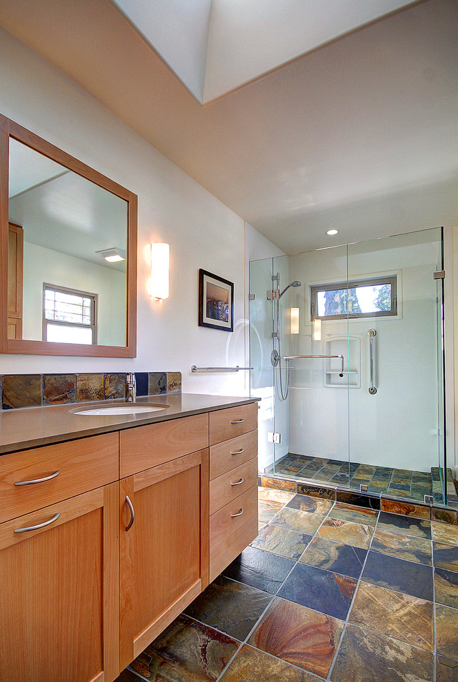 Réalisation d'une salle d'eau minimaliste en bois brun de taille moyenne avec un lavabo encastré, un placard à porte shaker, un plan de toilette en surface solide, une douche d'angle, un carrelage multicolore et un mur blanc.