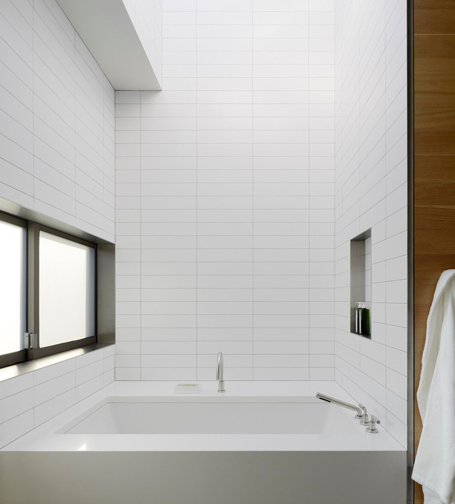 Foto di una stanza da bagno padronale minimalista di medie dimensioni con ante in legno scuro, vasca ad alcova, piastrelle bianche, piastrelle in pietra e pareti gialle