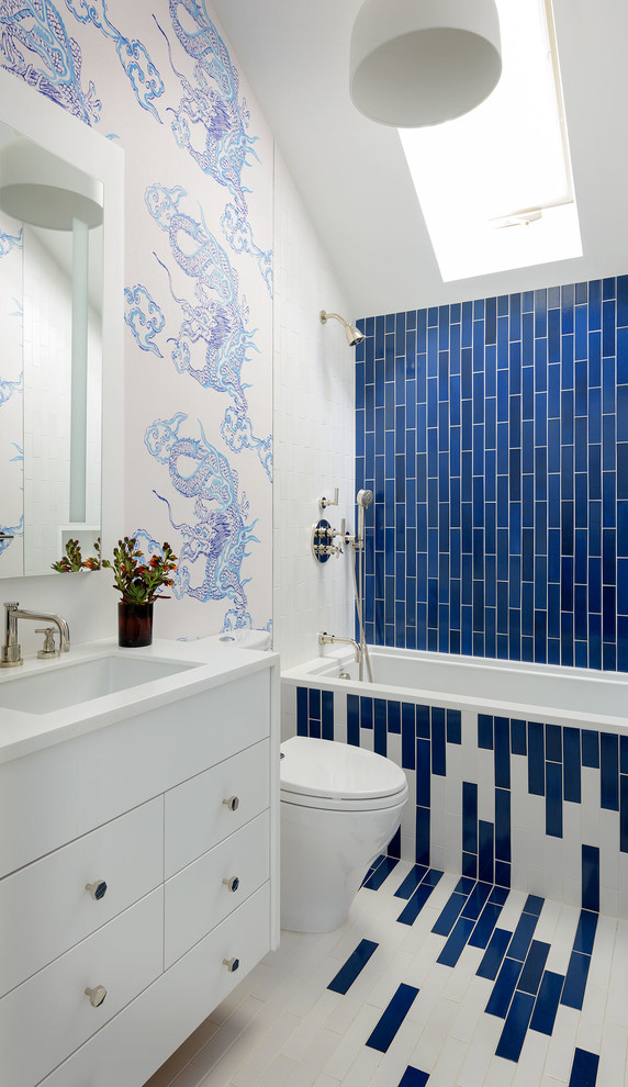 サンフランシスコにある高級な中くらいなトランジショナルスタイルのおしゃれな子供用バスルーム (白いキャビネット、シャワー付き浴槽	、一体型トイレ	、セラミックタイル、マルチカラーの壁、セラミックタイルの床、アンダーカウンター洗面器、人工大理石カウンター、フラットパネル扉のキャビネット、アルコーブ型浴槽、青いタイル、オープンシャワー) の写真