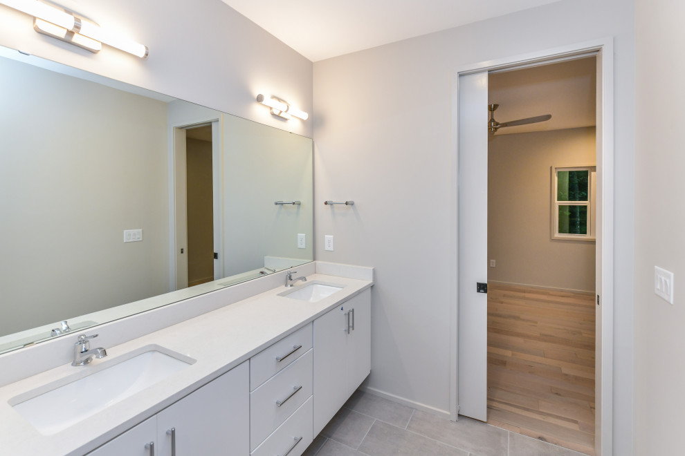 Large modern ensuite bathroom in Charlotte with flat-panel cabinets, white cabinets, a freestanding bath, a corner shower, porcelain tiles, white walls, a submerged sink, white floors, an open shower and white worktops.