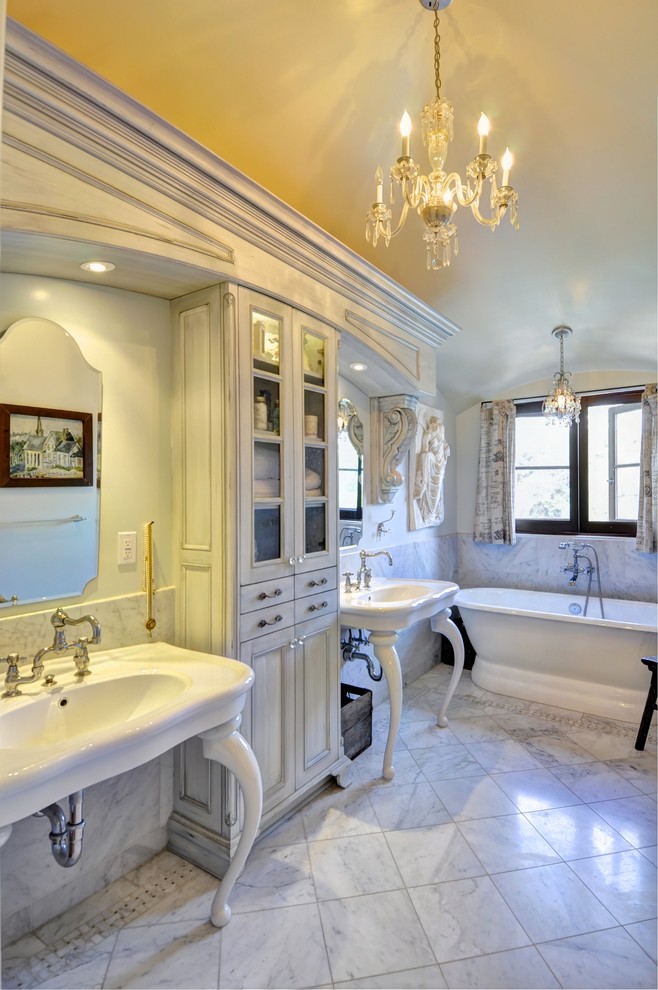 Пример оригинального дизайна: ванная комната в стиле рустика с раковиной с пьедесталом, фасадами с утопленной филенкой, искусственно-состаренными фасадами, отдельно стоящей ванной, двойным душем, унитазом-моноблоком, серой плиткой и каменной плиткой