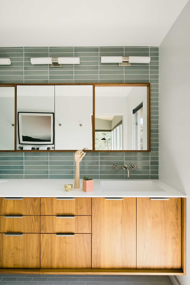 На фото: ванная комната в современном стиле с плоскими фасадами, фасадами цвета дерева среднего тона, серой плиткой, зеленой плиткой, монолитной раковиной, серым полом и зеркалом с подсветкой