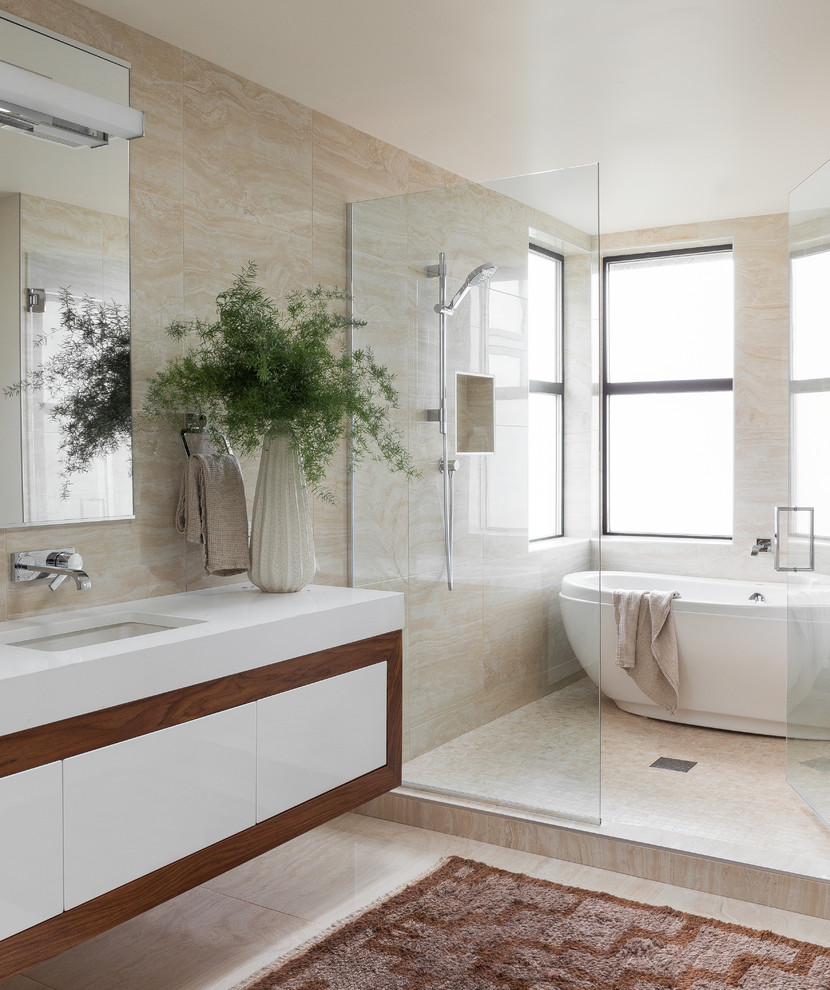 This is an example of a contemporary wet room bathroom in Seattle with flat-panel cabinets, white cabinets, a freestanding bath, beige tiles, beige walls, a submerged sink, beige floors, a hinged door and white worktops.
