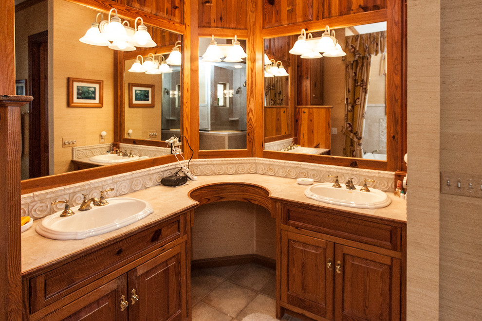 Exemple d'une salle de bain principale bord de mer avec un lavabo posé, un placard avec porte à panneau surélevé, des portes de placard beiges, un plan de toilette en granite, une douche d'angle, un mur beige et un sol en travertin.