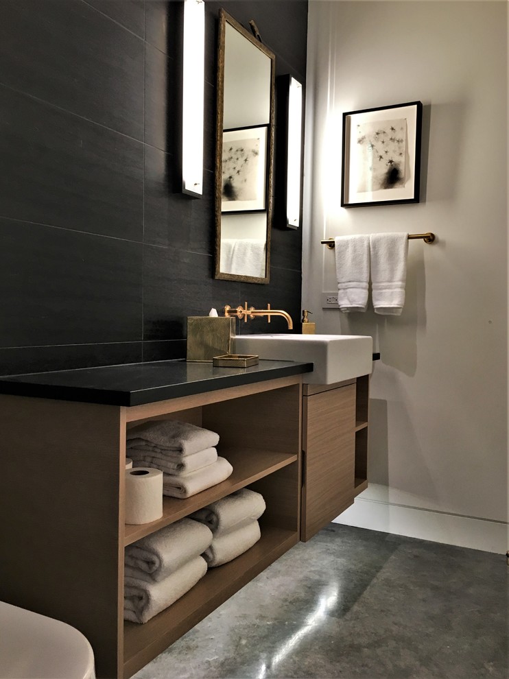 This is an example of a medium sized contemporary shower room bathroom in Other with flat-panel cabinets, light wood cabinets, a built-in shower, a one-piece toilet, black tiles, grey walls, concrete flooring, a built-in sink, grey floors and a hinged door.