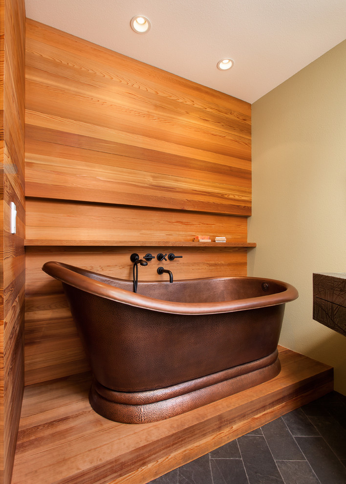 Пример оригинального дизайна: главная ванная комната среднего размера в современном стиле с плоскими фасадами, зелеными фасадами, отдельно стоящей ванной, раздельным унитазом, оранжевыми стенами, монолитной раковиной, мраморной столешницей, полом из сланца и черным полом