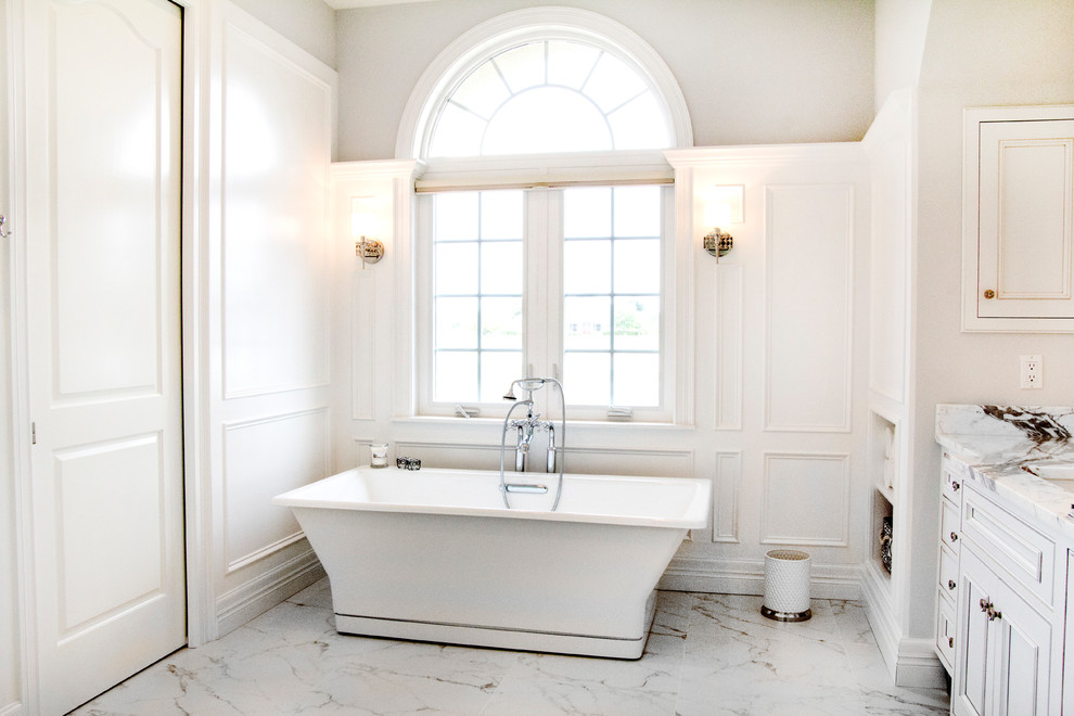 Idée de décoration pour une grande douche en alcôve principale tradition avec un placard à porte affleurante, des portes de placard blanches, une baignoire indépendante, un carrelage blanc, un carrelage de pierre, un mur beige, un sol en marbre, un lavabo encastré et un plan de toilette en marbre.