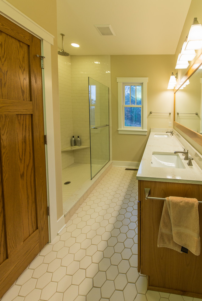 Foto på ett stort amerikanskt en-suite badrum, med skåp i shakerstil, skåp i mellenmörkt trä, en dusch i en alkov, vit kakel, tunnelbanekakel, beige väggar, klinkergolv i porslin, ett undermonterad handfat, bänkskiva i kvarts, vitt golv och dusch med skjutdörr