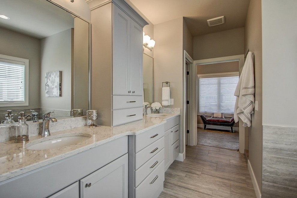 Пример оригинального дизайна: большая главная ванная комната в стиле неоклассика (современная классика) с фасадами с утопленной филенкой, серыми фасадами, раздельным унитазом, серыми стенами, полом из керамогранита, врезной раковиной, шторкой для ванной, отдельно стоящей ванной, угловым душем, мраморной столешницей и коричневым полом