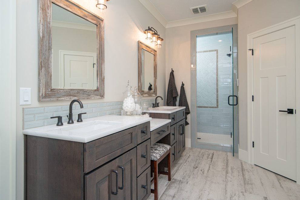 Bathroom - large transitional master gray tile and porcelain tile porcelain tile and white floor bathroom idea in Grand Rapids with raised-panel cabinets, brown cabinets, a two-piece toilet, gray walls, an undermount sink, marble countertops, a hinged shower door and white countertops