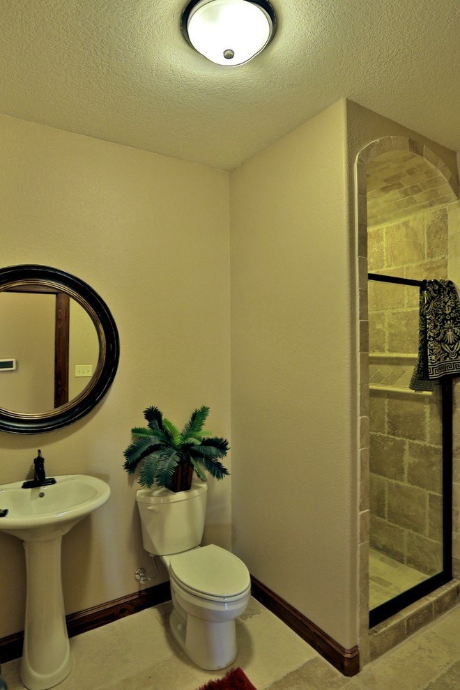Mediterranes Badezimmer mit Sockelwaschbecken, Duschnische, Wandtoilette mit Spülkasten, braunen Fliesen, Steinfliesen, beiger Wandfarbe und Travertin in Dallas